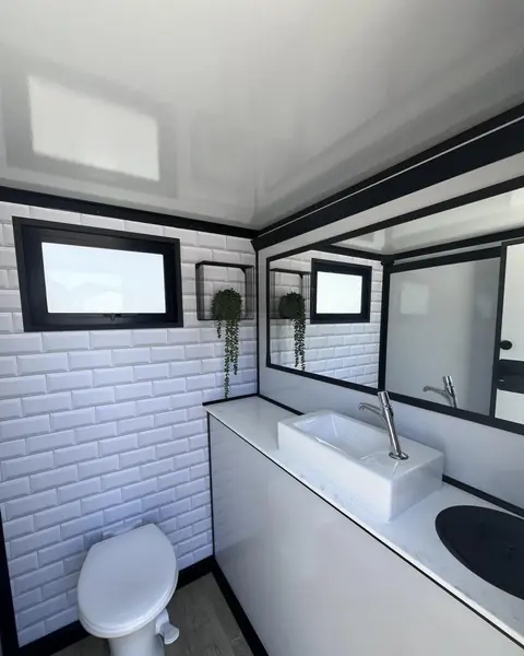 Tiled restroom trailer interior with a vessel sink and mirror