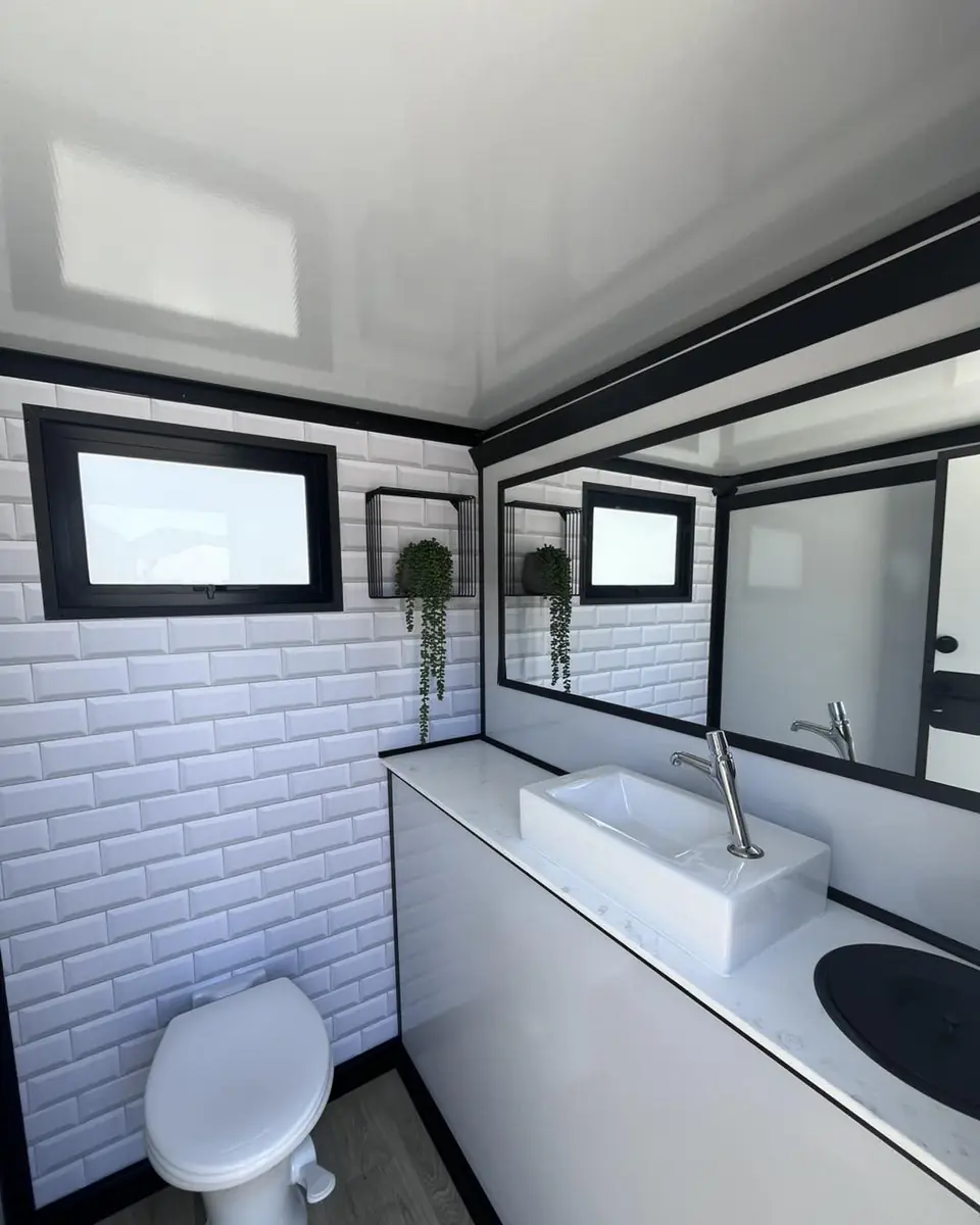 Luxury restroom trailer interior with white tile, vessel sink and mirror