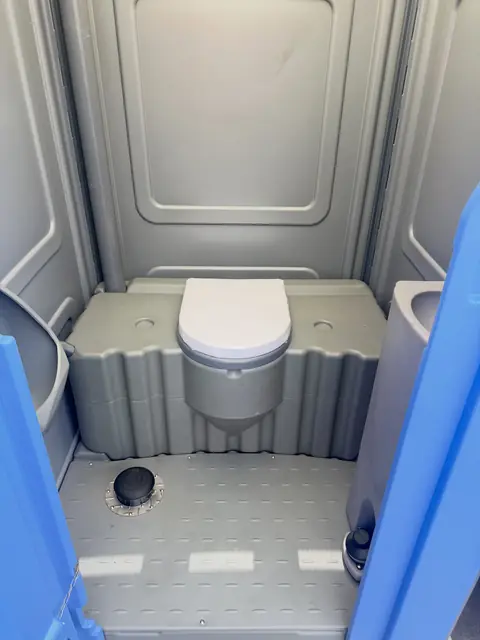 Clean porta potty interior with a closed seat and bare floor