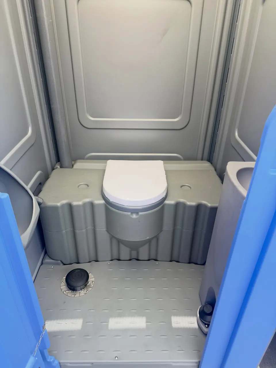 Clean porta potty interior with a closed seat and clear floor