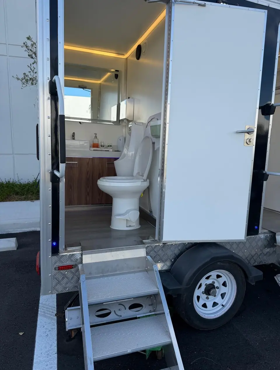 Restroom trailer stall with a porcelain toilet and wood vanity