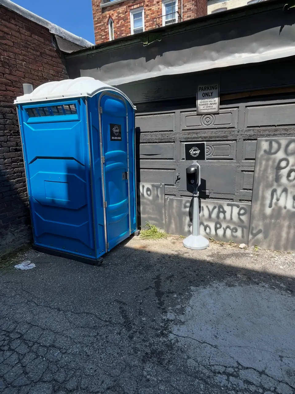 Standard porta potty placed in a paved alley