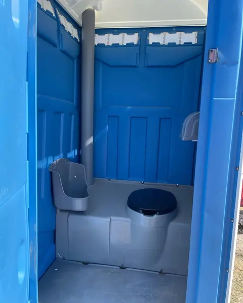 Porta potty interior showing the toilet seat, urinal and paper holder