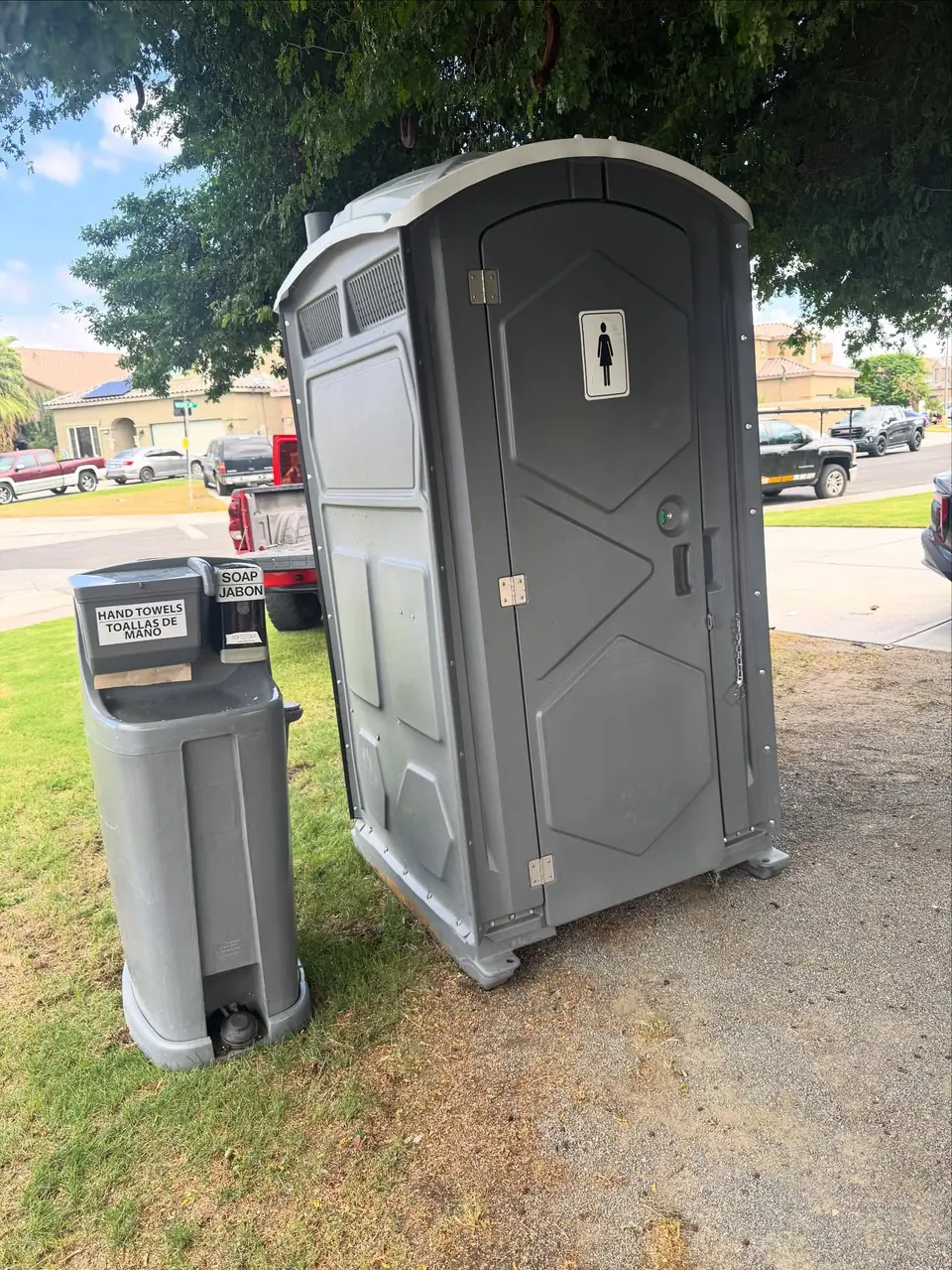 Standard porta potty with a hand wash station on grass
